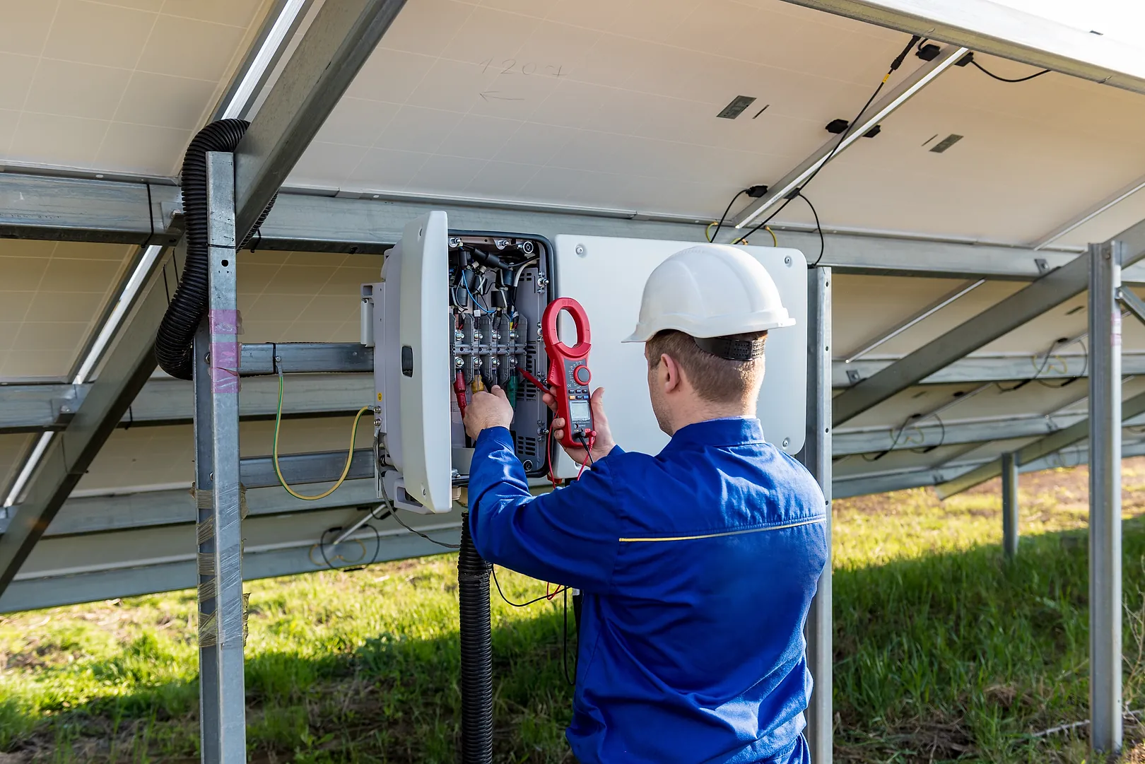 Técnico de capacete inspecionando o quadro de um sistema solar