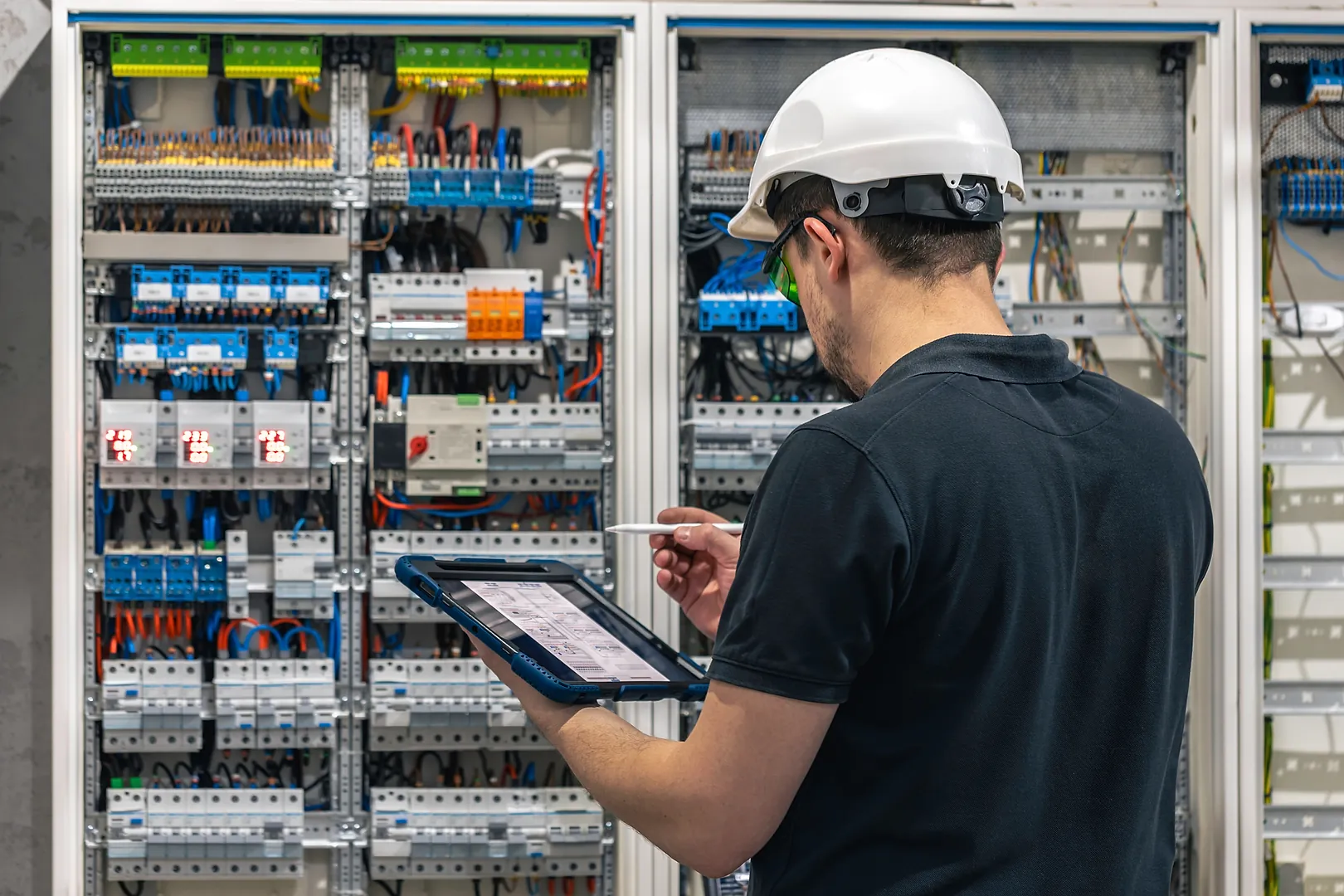Eletricista conferindo um quadro elétrico com um tablet